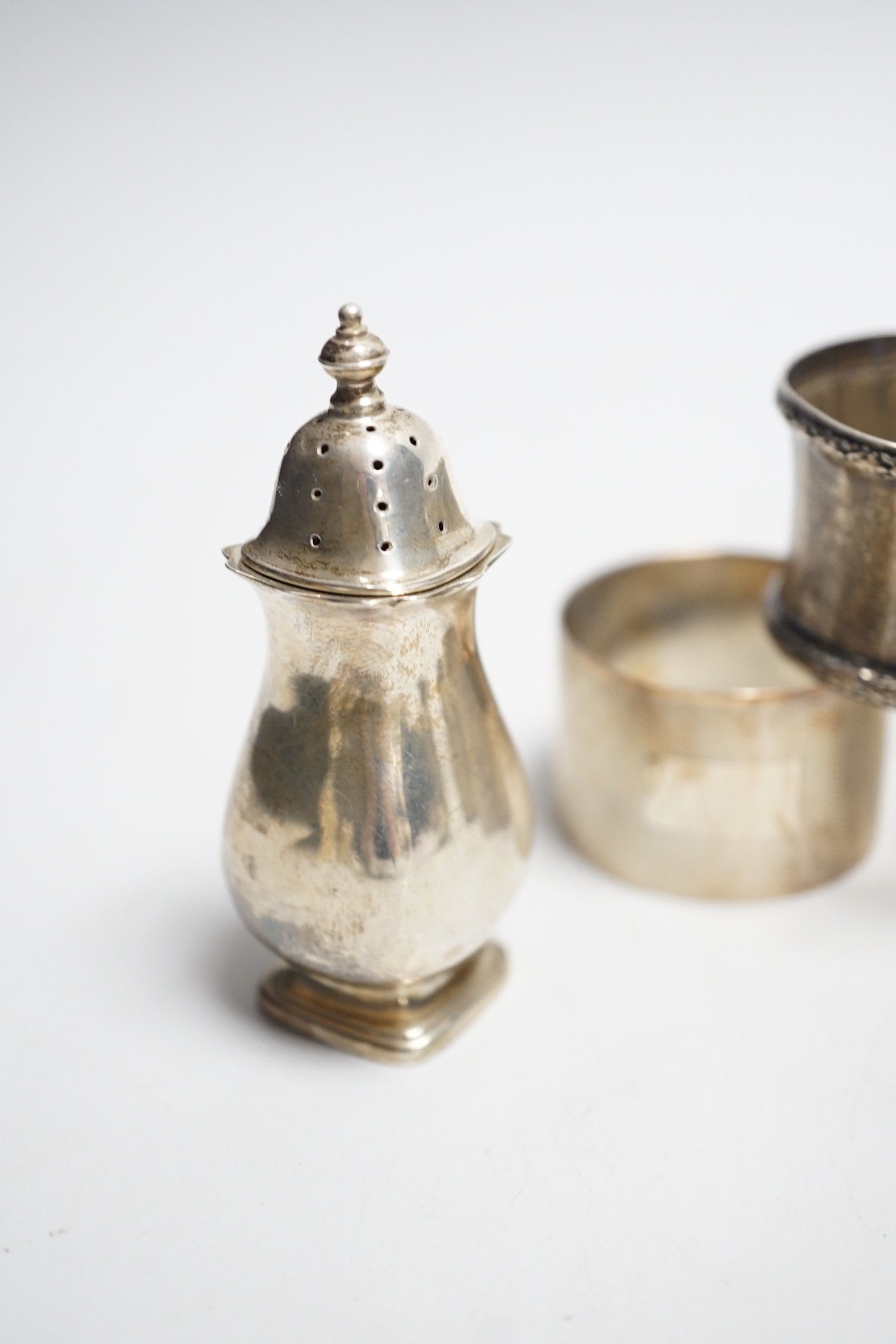 Five assorted silver napkin rings and a George V silver three piece condiment set.
